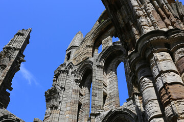 Whitby Abbey stands majestically with its gothic architecture against a clear sky. Captured at a low angle, the ruins show the layers of stonework and arches at Whitby Abbey - Whitby - North Yorkshire