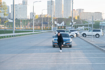Caucasian man pulling a car with a rope. 