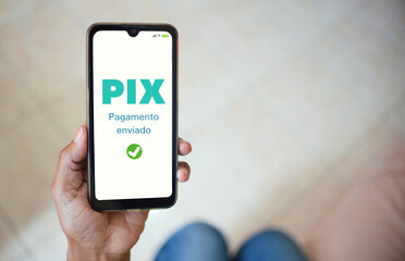 Payment with Pix. A woman holding a cell phone with payment confirmation on the screen. Illustrative image.