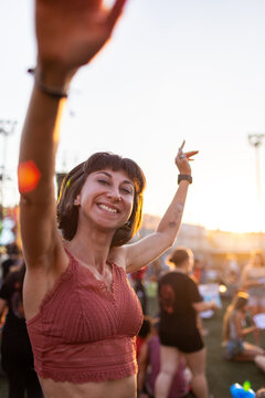 Young woman dancing at concert, having fun at night on open air stage. Sexy woman enjoying music at concert. Cheerful girl hanging out at dance party.