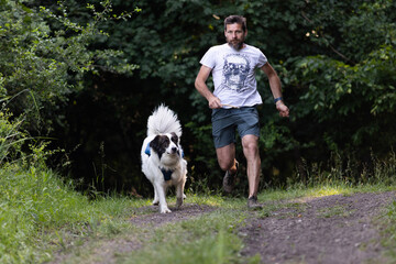 happy man and dog running in forest