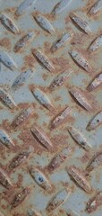 Rusty metal sheet with diamond plate pattern. Aged surface showing corrosion, peeling paint, and rough industrial texture perfect for grunge backgrounds.