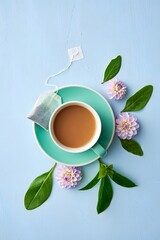 Tea cup with flowers and leaves on blue background for relaxation and wellness drink