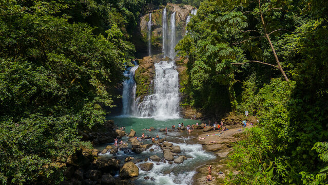 Nauyaca Waterfall in Perez Zeledon, San Jose, Costa Rica. Aerial drone footage of beautiful multi-stage waterfall. With Tourists swimming and enjoying the waterfall. 