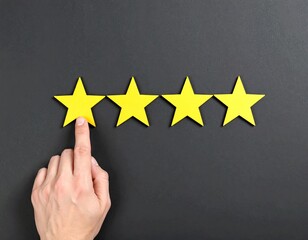 Hand pointing at four yellow stars on dark background