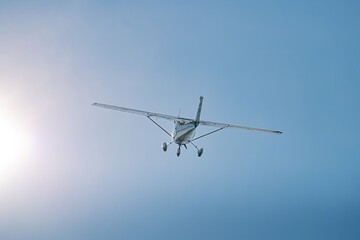Wide-angle, low front view of a high-wing general aviation aircraft climbing with landing gear...