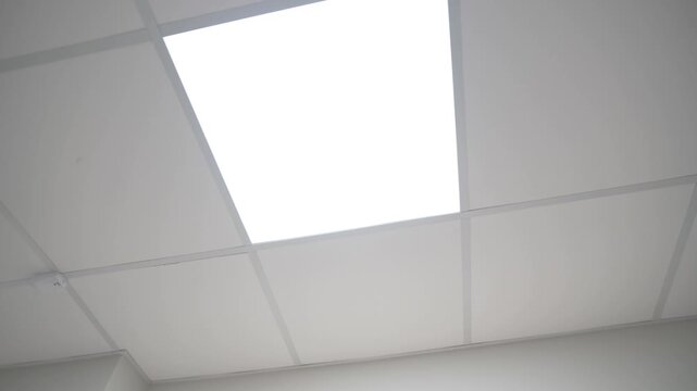 Glowing square led lamp on suspended ceiling in office low angle shot. Bright lighting equipment illuminates lobby of public building