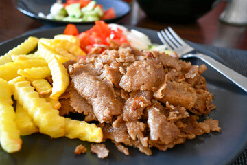 Lamb doner kebab with french fries chips and vegetables salad. Traditional Turkish food.
