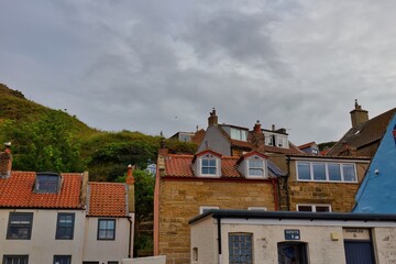 A row of buildings under a cloudy sky. The buildings have varied architecture. Some have red tile roofs  in Staithes - North Yorkshire - United Kingdom