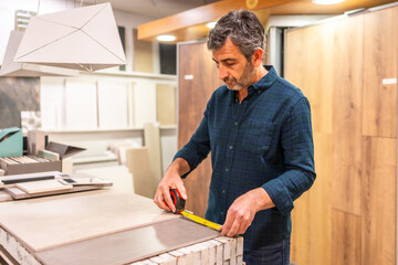 Tiler measuring ceramic tile in home improvement store