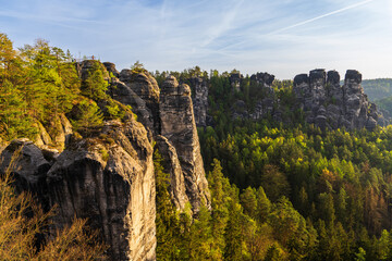 Majestic sandstone rock formations rise above green forests in Saxon Switzerland National Park, Germany. Famous landscape for hiking, tourism, outdoor photography.