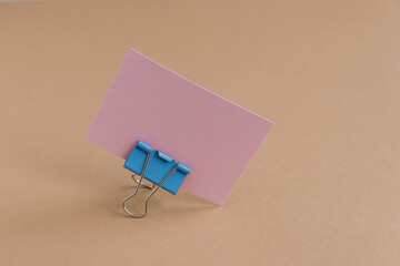 A pink card with space for text, placed on a brown background using a clip.