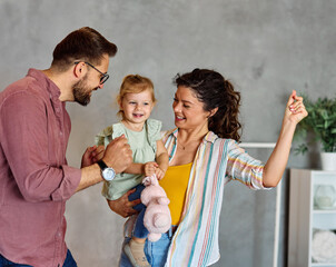 Portrait of mother, father and daughter having fun dancing at home, family life, parenting, love and bonding concepts