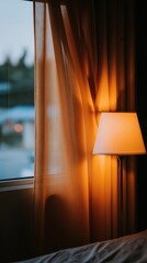 A warm and inviting interior scene features a soft, glowing lamp, casting gentle light and shadows on the bed and curtains.