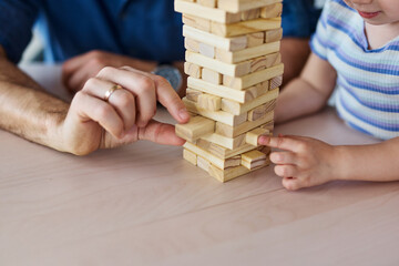 Portrait of a happy family at home, having fun playing wooden brick challenge game, playing board...