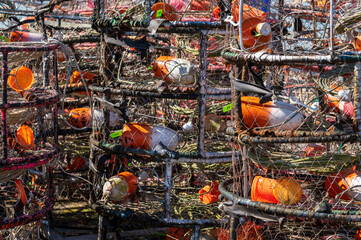 Closeup of Crab Pots stacked on the wharf with colorful floats inside the cage. When not in use the pots are stored on shore with the line and floats stored inside ready for use.