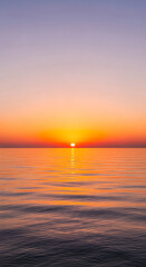 Serene sunset over calm ocean water, showcasing warm orange and purple hues reflecting on the surface, symbolizing tranquility and peace