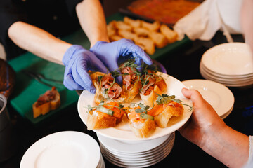 Gloved hands serving gourmet appetizers on plate