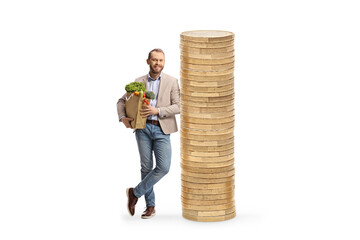 Full length portrait of a young casual man holding a grocery bag and leaning on coins