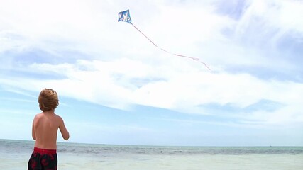 Little boy flying kite on beach