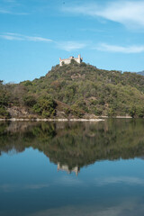 Beautiful autumn scene with lake, hills, castle in Piedmont. Wide scenic shot of Alpine mountains and lake with vibrant summer colors, ideal for adventure, hiking, and nature photography themes.