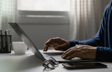 Close-up of man typing on laptop at home office, freelance work, online business, remote communication concept. Remote working, freelancer lifestyle, creative project, digital technology, modern work.