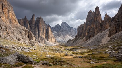 Jagged mountain cliffs towering above rocky valley under cloudy afternoon sky