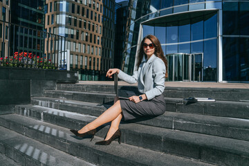 A woman stands poised in front of a reflective office building, dressed in business attire, ready to seize the day.