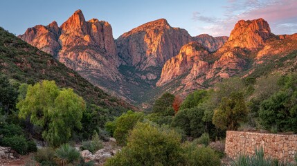 Sunrise over mountain range with soft orange light illuminating peaks and valleys