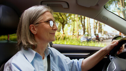 Naklejka premium Carefree active Caucasian pensioner positive owner elderly woman buyer senior mature female auto driver riding inside automobile driving vehicle dancing music song enjoying good quality audio radio
