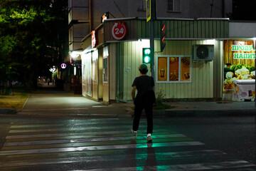 Evening stroll across the street in a quiet urban neighborhood with green traffic signal