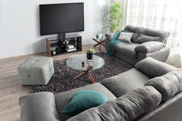 Wide-angle top view of a modern living room featuring gray modular sofas, round glass coffee table,...