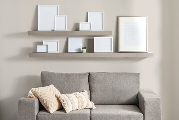 Modern living room wall composition with two oak floating shelves displaying a variety of blank...