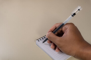 A hand writing with a ballpoint pen on an open notebook