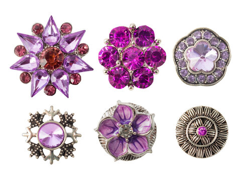 Isolated photo of sparkling purple and lilac flower buttons / brooches or pendants with gemstones on white backdrop.