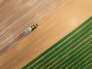 Obraz premium In spring, farmers use farm machinery to grow peanuts，Aerial photos of farmers using agricultural machinery to cultivate the land.