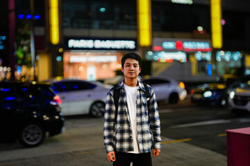 a young man standing on a street at night showing of a night bokeh photography