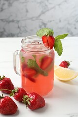 Refreshing drink with strawberries and mint on white table against grey marble background, closeup
