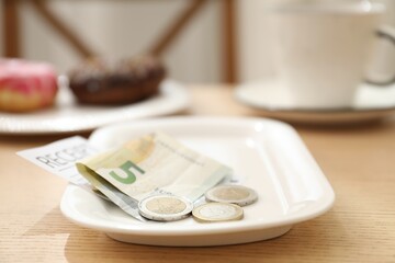 Tips and receipt on wooden table in restaurant, closeup. Gratuity for work