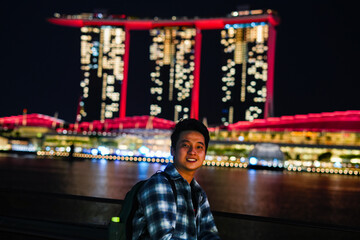 Fototapeta premium young man portrait near marina bay sands in singapore in night time