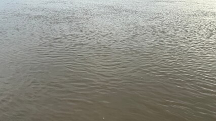 The flowing river reflects sky and light, creating an abstract water surface texture