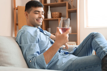 Young man with glass of pink wine at home