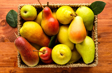 Wicker box with ripe pears on wooden background