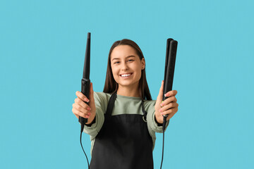 Female hairdresser with curling iron  and flattening iron on blue background
