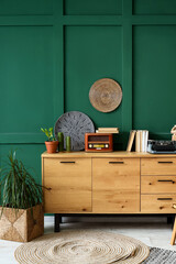 Vintage typewriter with books and radio receiver on commode near green wall in room