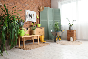 Chest of drawers, pegboard and gardening tools in interior of workshop