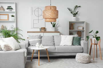 Interior of light living room with grey sofas, shelf units and plants