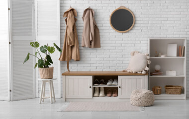 Obraz premium Folding screen, houseplant and bench near white brick wall in hallway