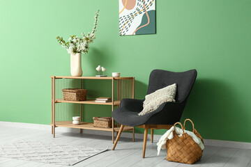 Interior of stylish living room with grey armchair and blooming tree branches on table