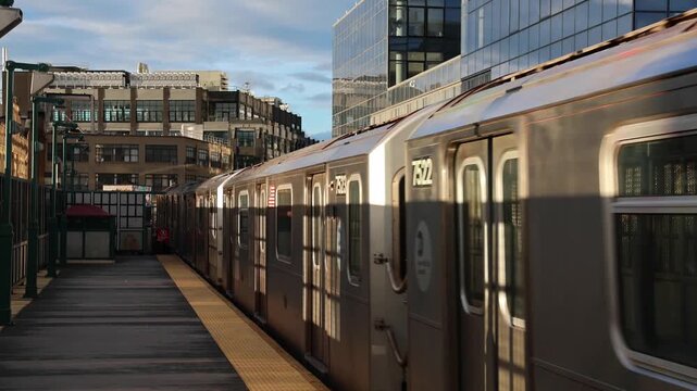 train arriving on platform in court square queens long island city new york nyc famous outdoor elevated station stop seven 7 metro commuter line tall buildings in background tracks railroad track